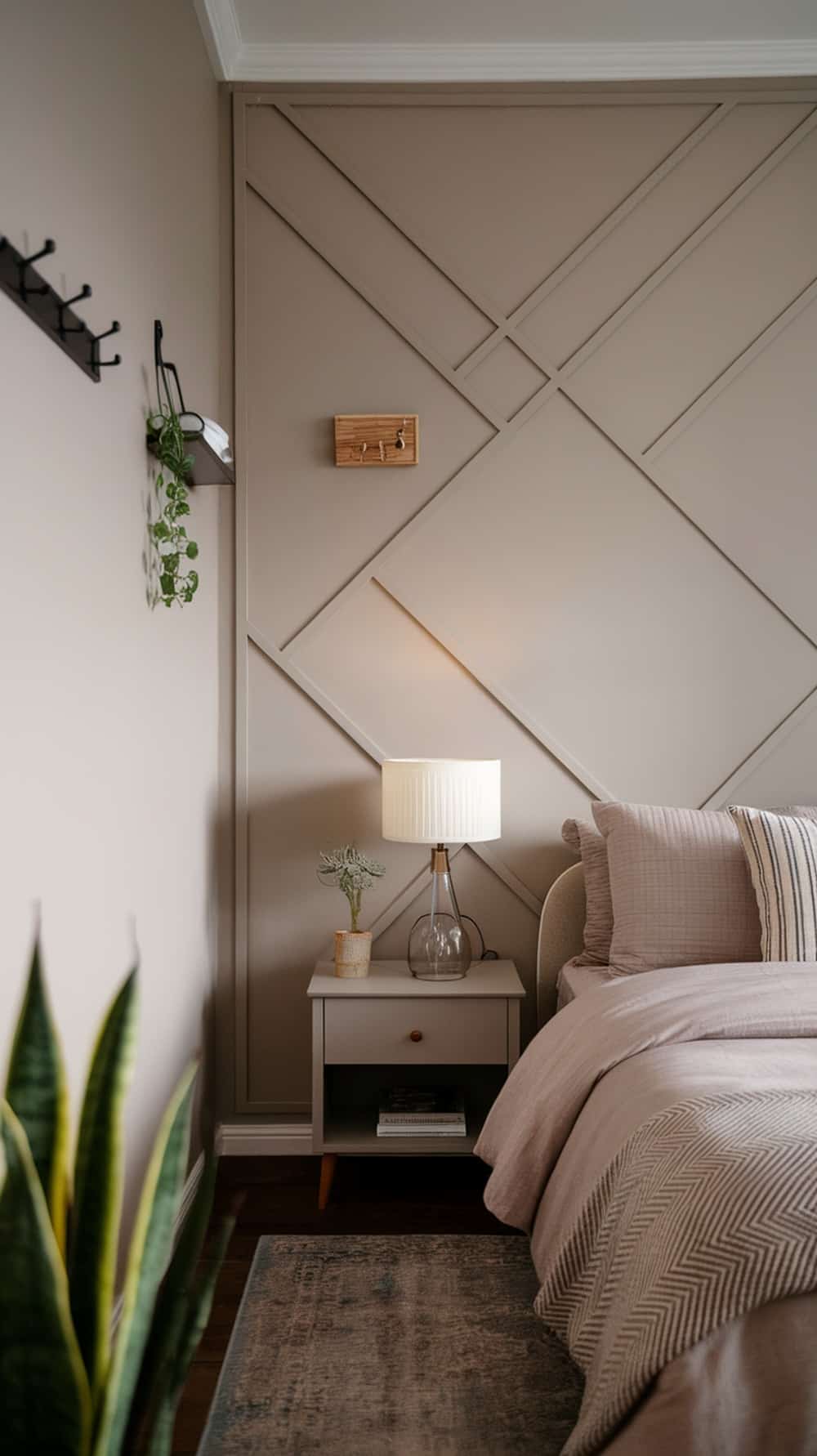A cozy bedroom featuring a greige accent wall with a subtle pattern, complemented by soft bedding and a stylish lamp.