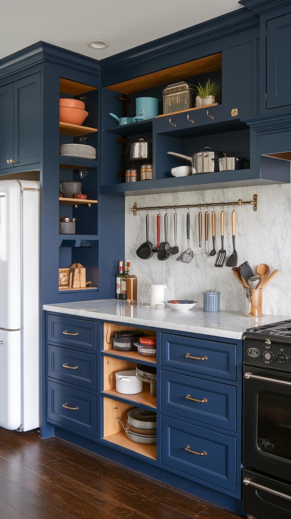 A modern kitchen featuring navy blue cabinets with smart storage solutions, including open shelving, organized drawers, and a hanging rack for utensils.