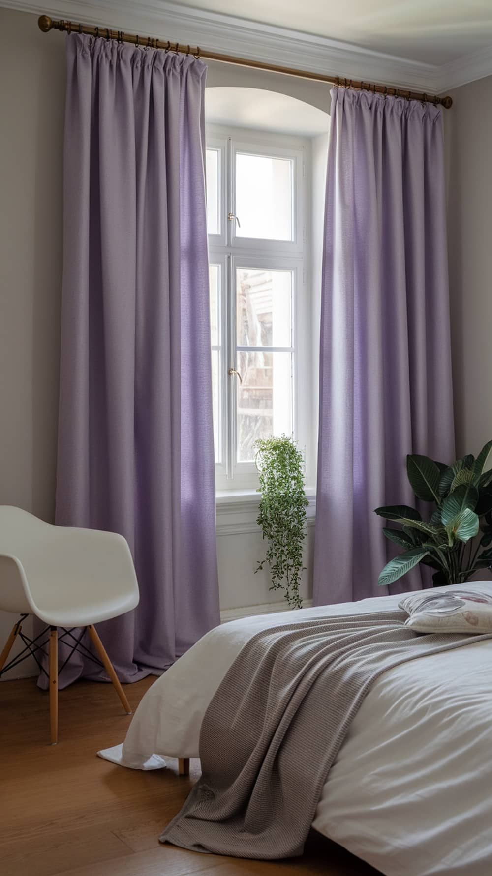 A cozy lavender bedroom with soft curtains and a plant by the window.