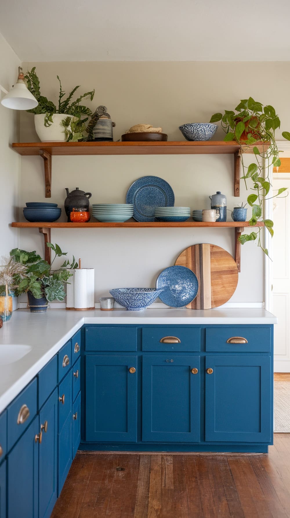 A kitchen featuring indigo cabinets and open wooden shelving displaying various dishes and plants.