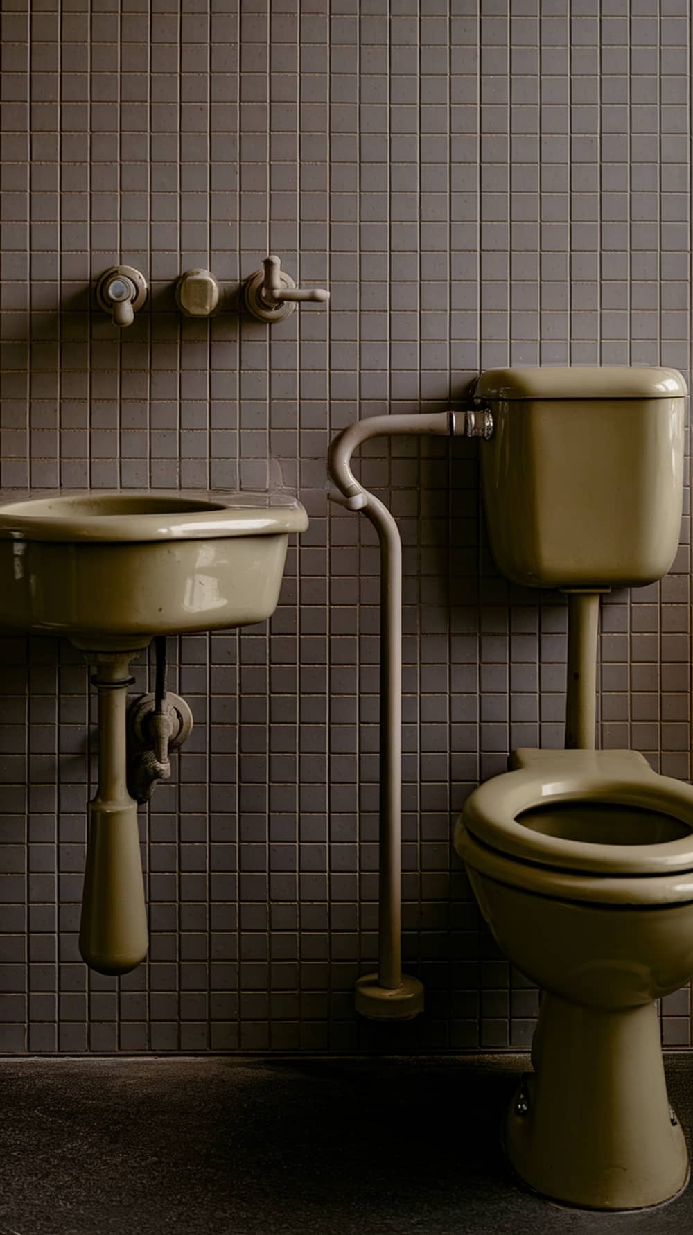 Mid-century modern bathroom fixtures including a sink and toilet in muted tones.