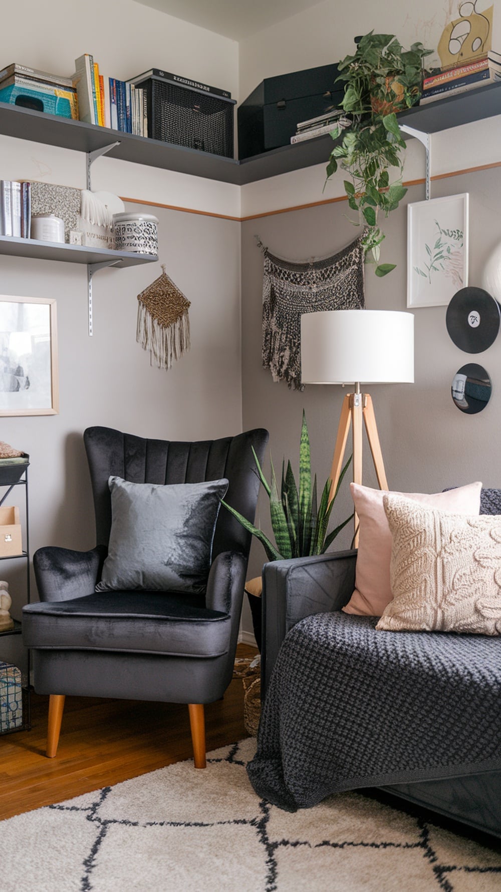 A cozy dorm room corner featuring a charcoal gray armchair, various textured pillows, a throw blanket, and decorative wall hangings.
