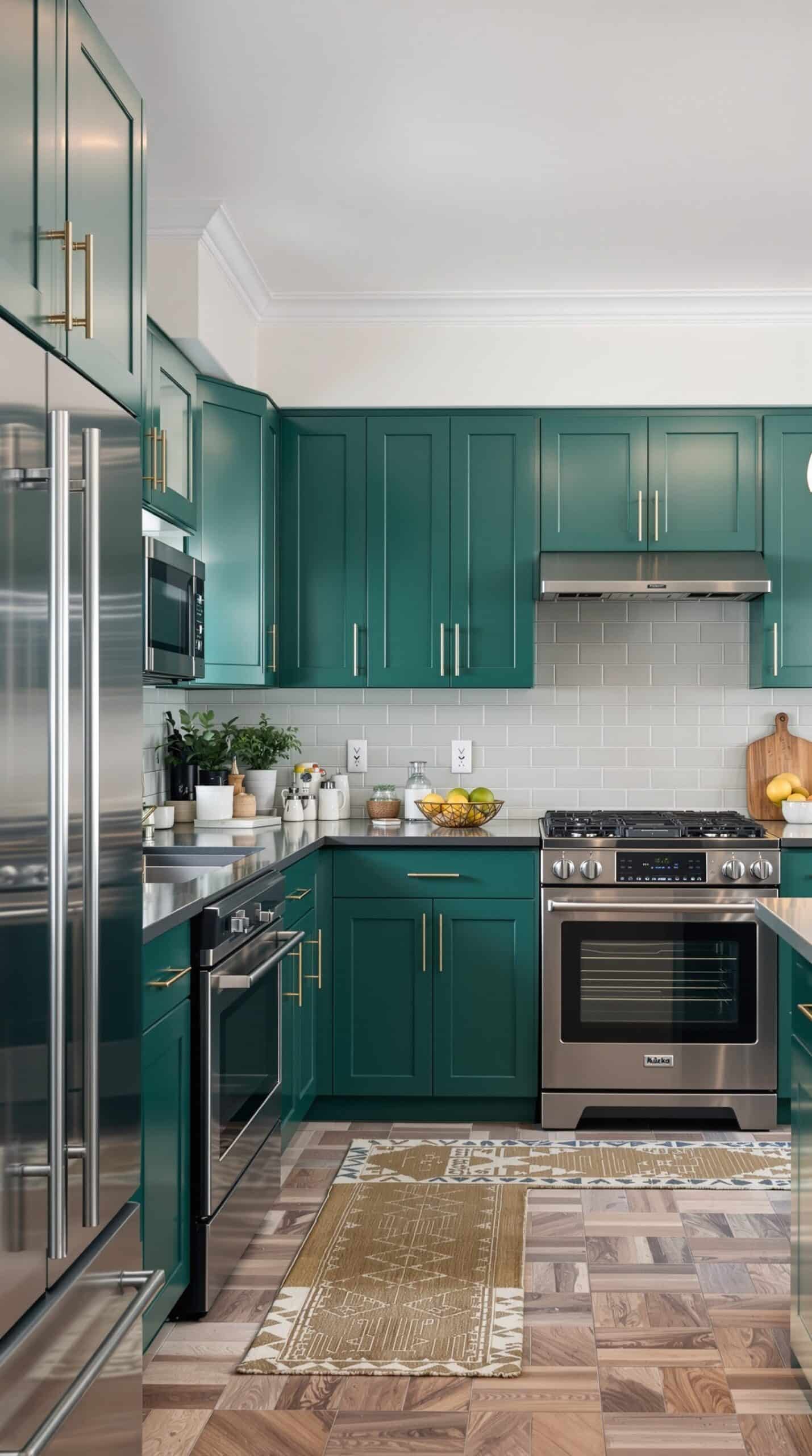 A modern kitchen featuring emerald green cabinets and sleek stainless steel appliances.