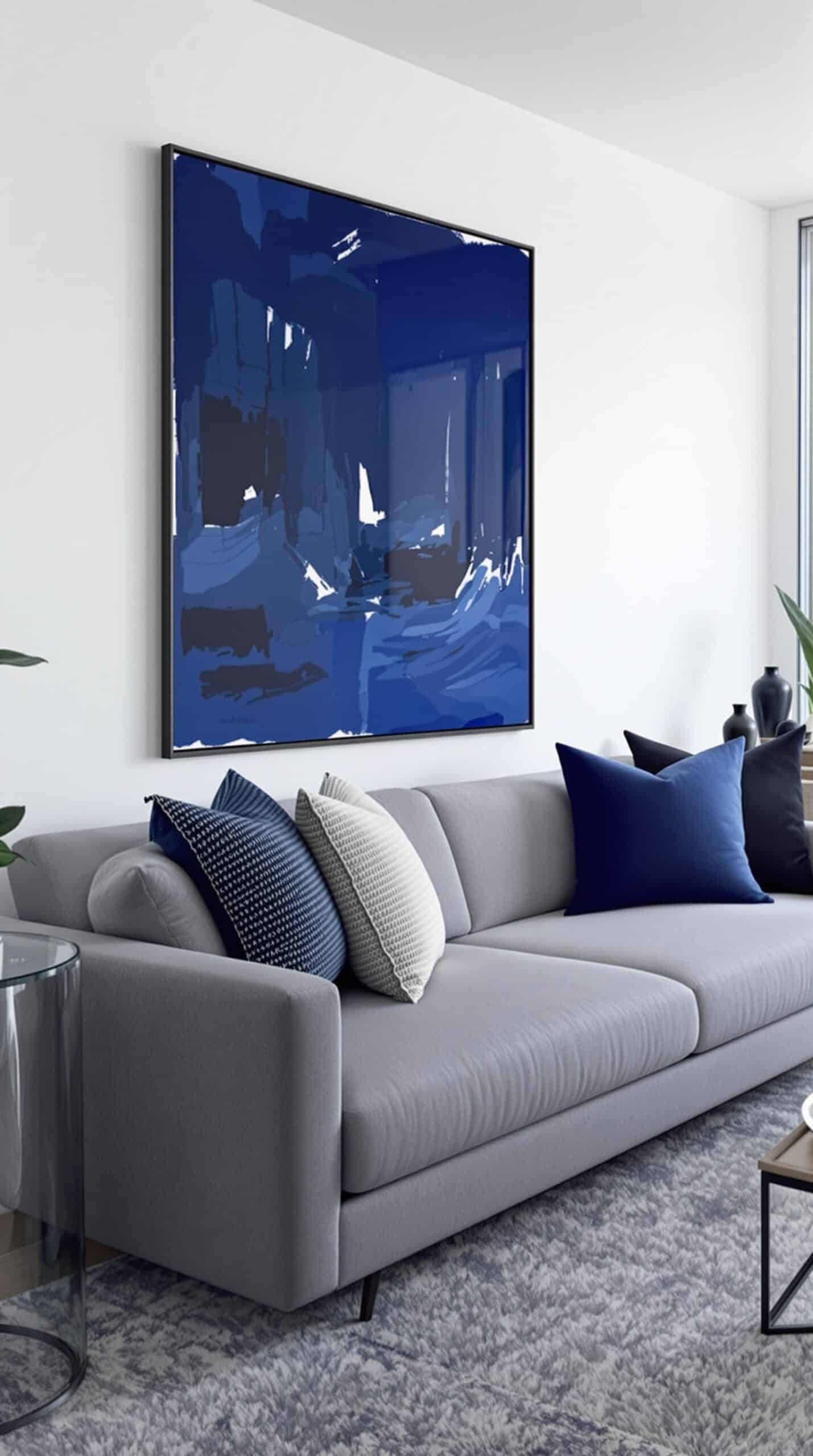 A modern living room featuring a large navy blue artwork with the word 'Tia' on the wall, complemented by a gray sofa and blue throw pillows.