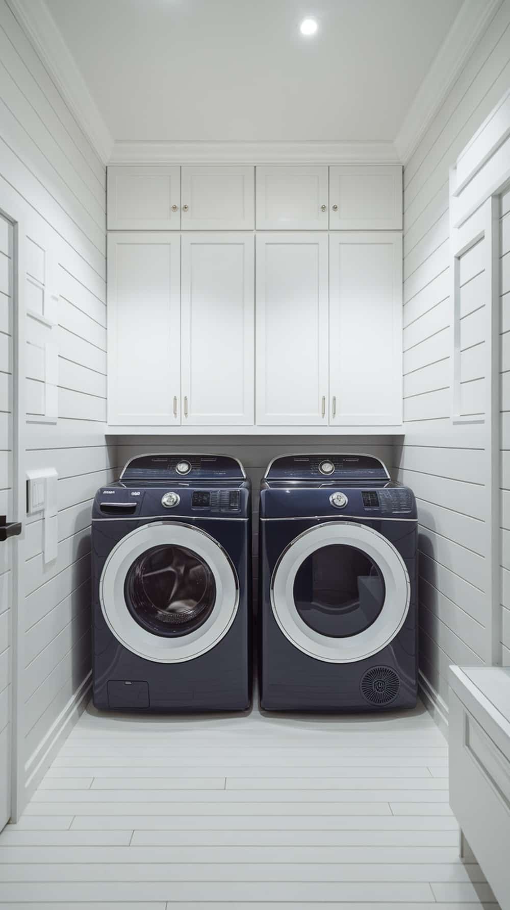 Laundry room featuring navy blue washing machines and white cabinetry