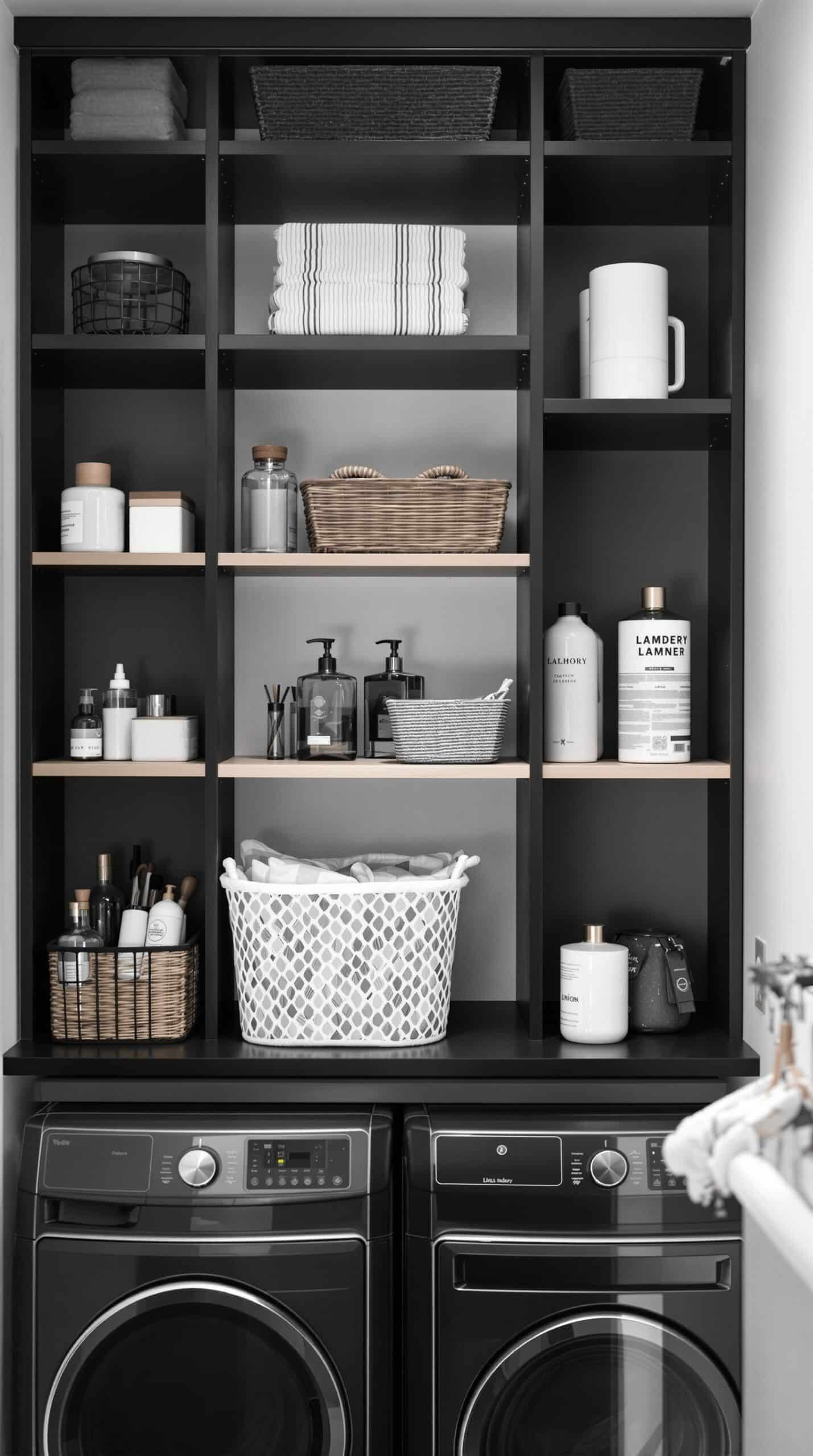 Minimalist black and white laundry room with open shelving displaying towels and storage baskets.