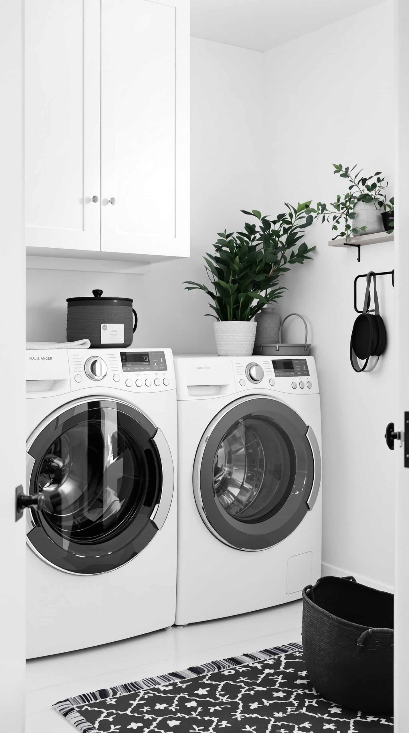 A minimalist laundry room with white walls, black accents, and modern appliances.