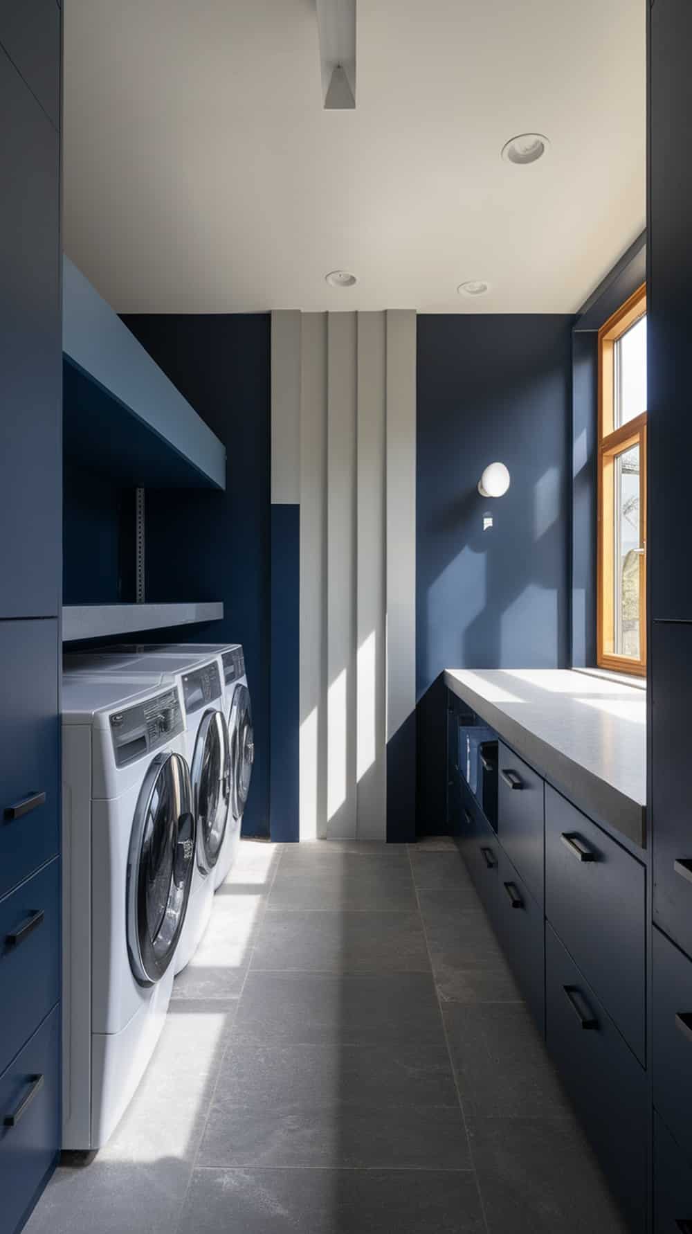 A modern laundry room featuring navy blue walls, gray countertops, and white appliances.