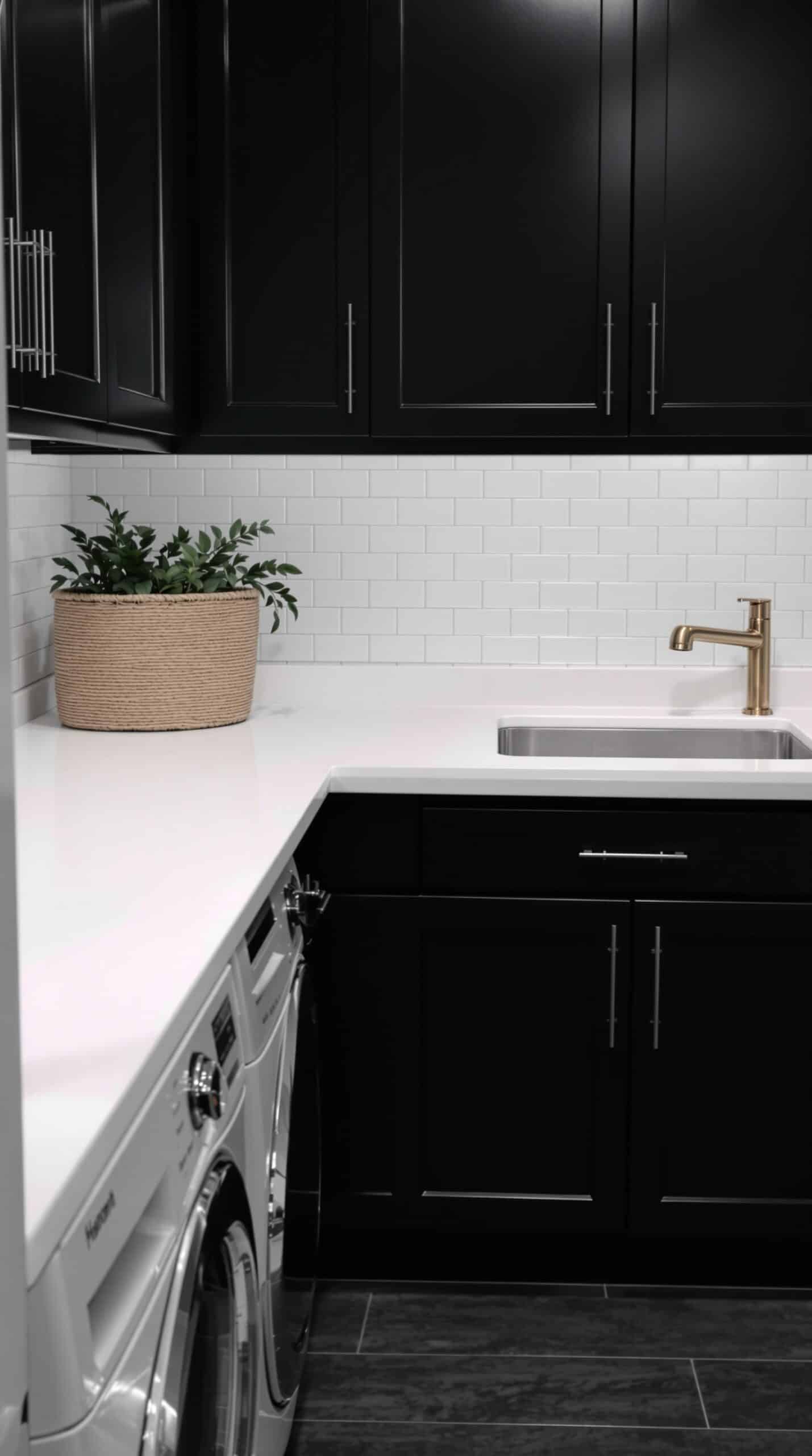 Modern laundry room with dark cabinets and bright white countertops
