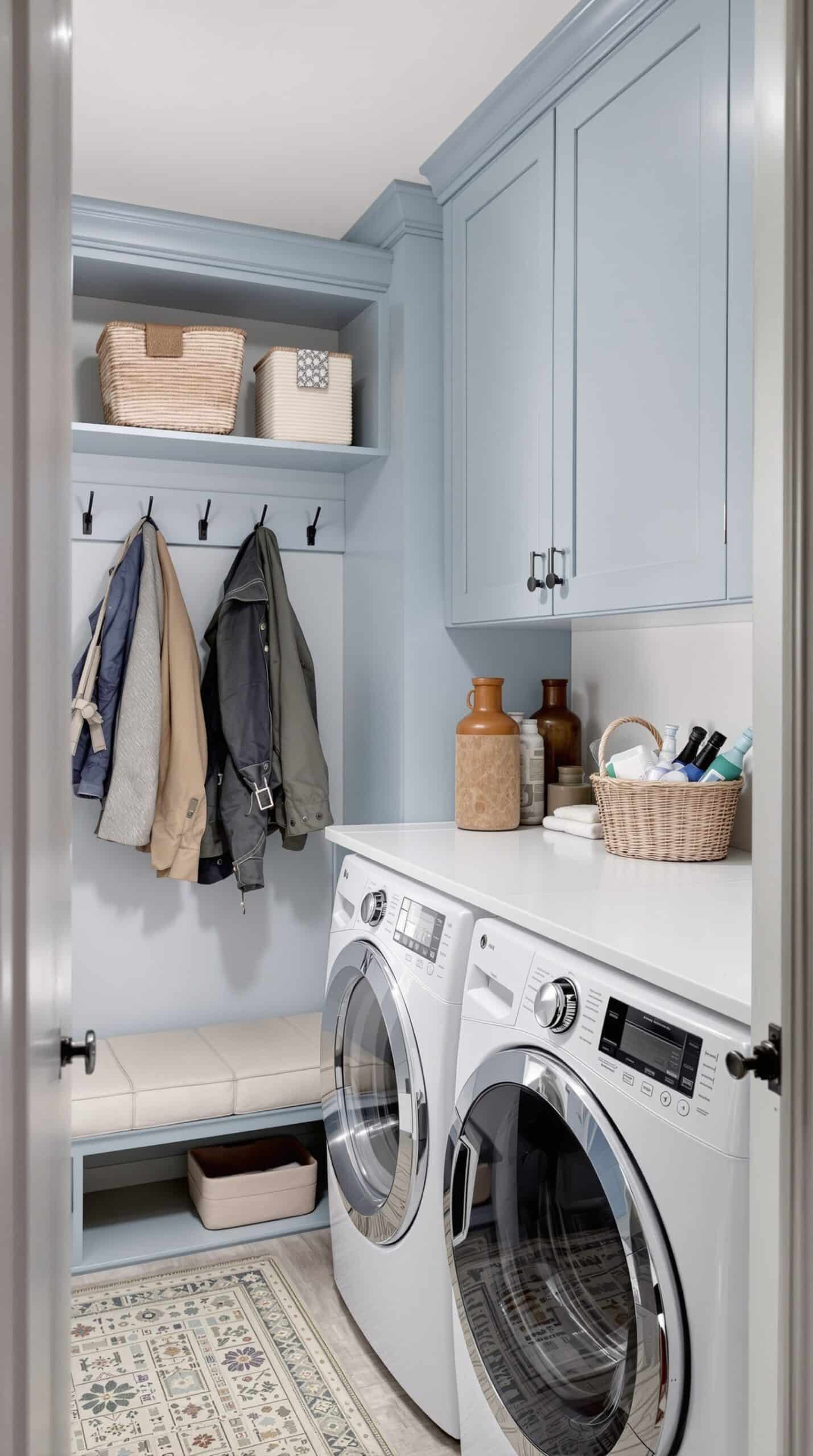 A functional mudroom laundry combo featuring dusty blue walls, white laundry machines, and organized storage.